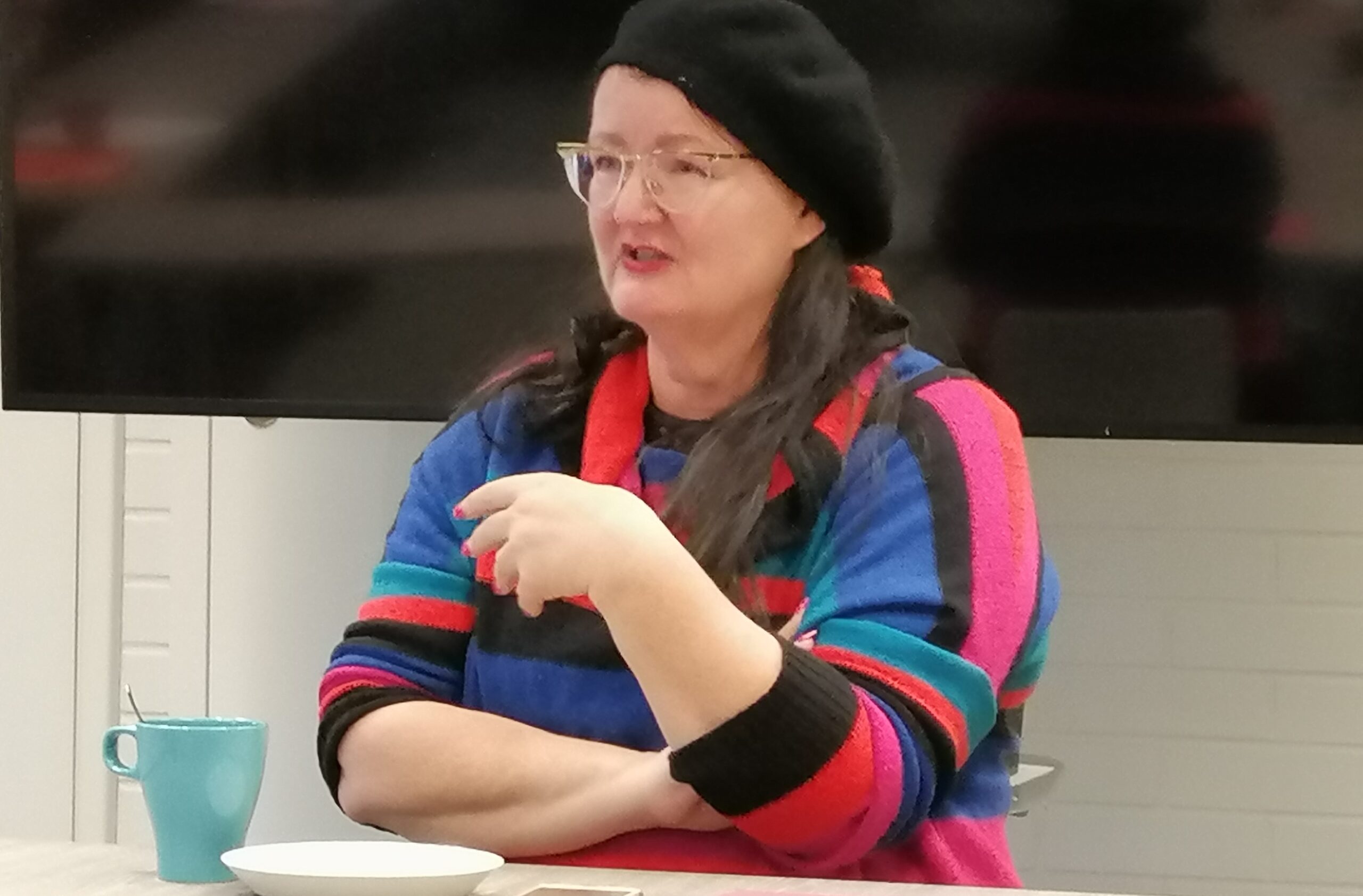 Anna-Stina Nykänen istuu pöydän ääressä kahvikuppi edessään