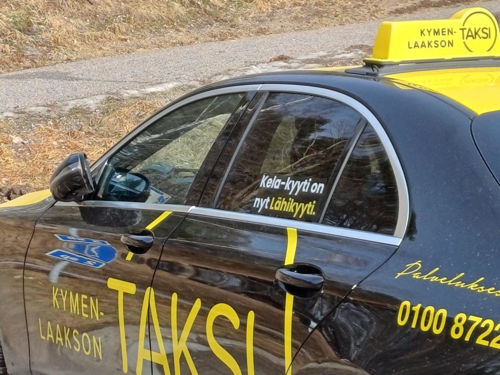 Taksi, jonka ikkunassa teksti Kela-kyydistä